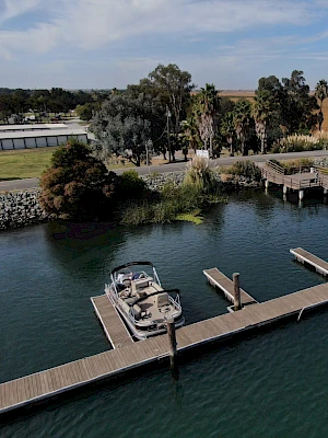 A peaceful marina with a boat docked along several piers, surrounded by water and greenery under a blue sky.